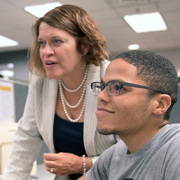 A woman training a man while both look at a screen