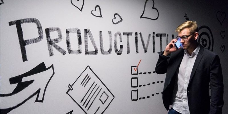 Man on phone walking by a wall that says Productivity