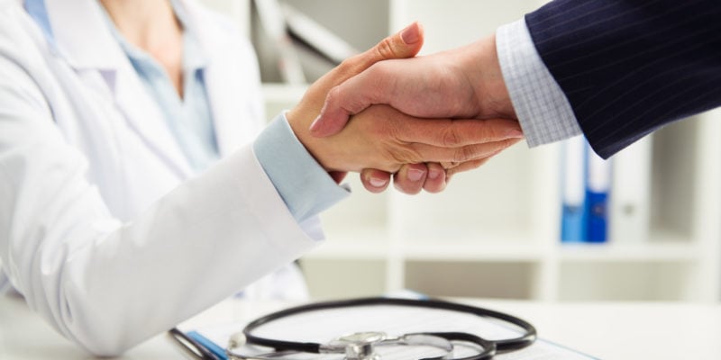 Woman doctor shaking hand with businessman in the office