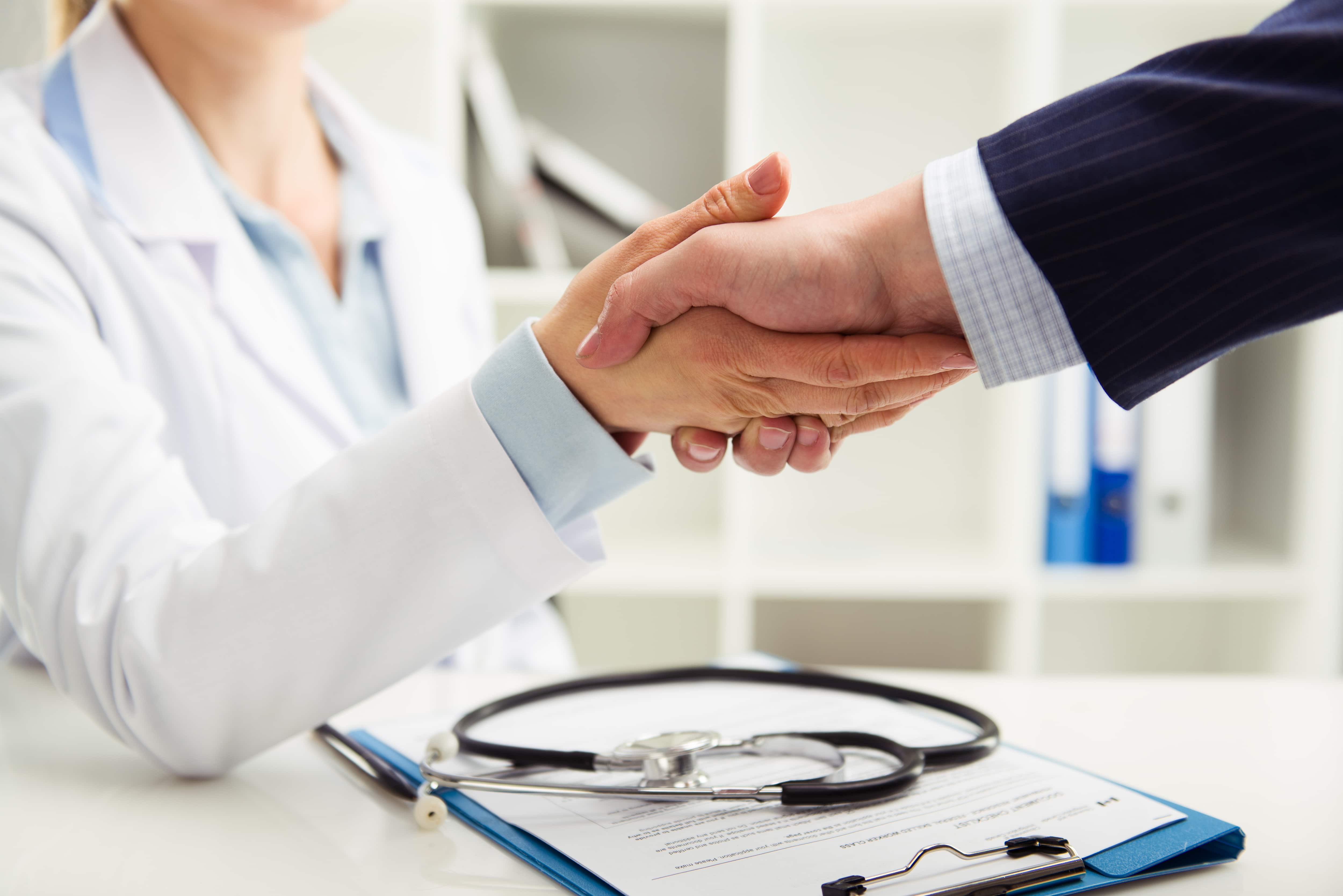 Woman doctor shaking hand with businessman in the office